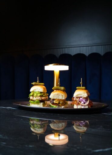 Three gourmet sliders presented on a black plate under warm lighting at Velvet Restaurant in Reading, Pennsylvania.
