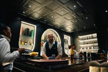 Two cocktails served at the bar with guests and warm floral décor in the background at Velvet Restaurant in Reading, Pennsylvania.