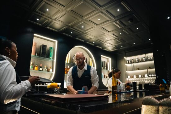 Two cocktails served at the bar with guests and warm floral décor in the background at Velvet Restaurant in Reading, Pennsylvania.