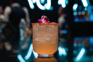 Signature cocktail displayed on the Velvet Restaurant bar with dramatic gold lighting and a glowing arch in the background.