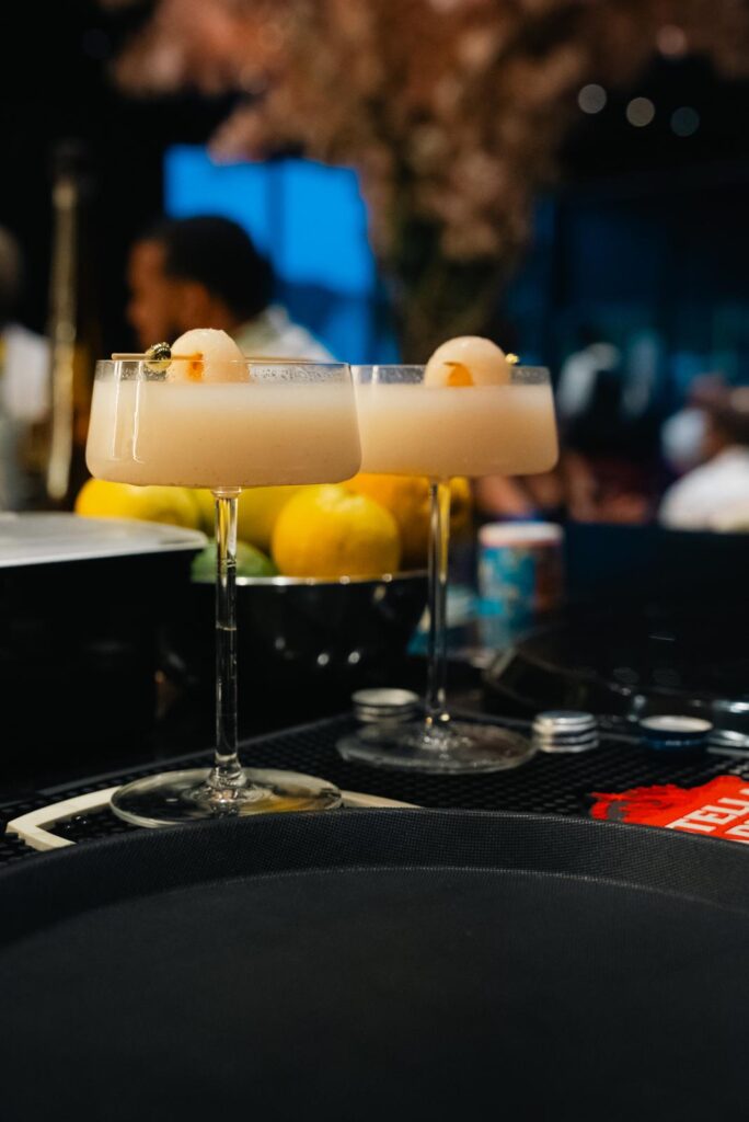 Two cocktails served at the bar with guests and warm floral décor in the background at Velvet Restaurant in Reading, Pennsylvania.